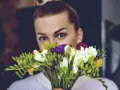 Kobieta z bukietem kolorowych frezji, jakby właśnie wyszła z kwiaciarni.