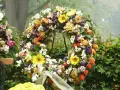 Bogaty wieniec pogrzebowy z róż, gerber, chryzantem i miechunki. Piękne kwiaty na wieniec pogrzebowy tworzą symboliczny bukiet.