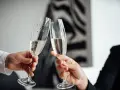 Dwie dłonie unoszą kieliszki z szampanem do toastu. To symboliczne rozpoczęcie ich srebrne wesele, pełne radości i nadziei.