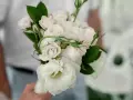 Delikatny bukiet z jednego kwiatu, otoczony pąkami róż i zielonymi liśćmi, tworzy romantyczną kompozycję.