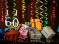 Urodzinowy muffin z cyframi 60, prezentami i serpentynami. Idealne życzenia na 60 urodziny!