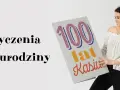 Uśmiechnięta koleżanka z pracy trzyma kartkę z napisem "Życzenia na urodziny 100 lat Kasiu".