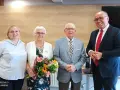 Para świętuje 65 rocznicę ślubu. Jubilaci z bukietem kwiatów, obok nich młodsza kobieta i mężczyzna w garniturze.