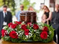 Czerwone róże i gipsówka otaczają urnę. Takie kwiaty na pogrzebie starszej osoby symbolizują miłość i pamięć.
