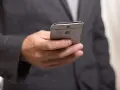 Mężczyzna w garniturze trzyma telefon, zastanawiając się, jak złożyć kondolencje przez telefon.