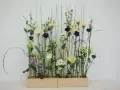 Kwiaty w pastelowych barwach i ciemnofioletowe akcenty, ułożone w stylu wegetatywnym we florystyce, tworzą lekki, naturalny bukiet.