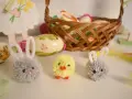 Urocze, proste ozdoby wielkanocne: puchate zajączki i kurczaczek, obok koszyka z pisankami.