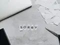 Litery wycięte z papieru układają się w napis "SORRY". Obok leżą nożyczki i stos białych skrawków, jakby ktoś tworzył piękny list na przeprosiny.