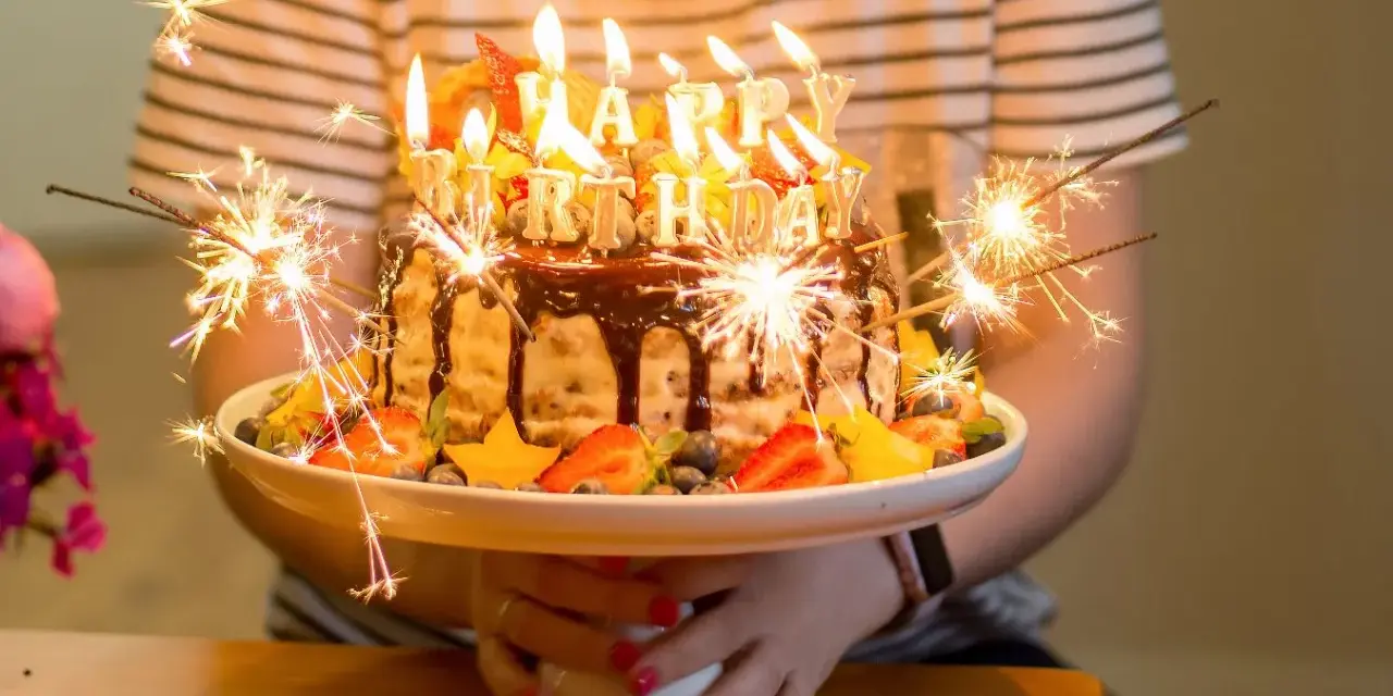 Urodzinowy tort z ogniem i owocami, idealny na mądre życzenia urodzinowe dla zięcia.