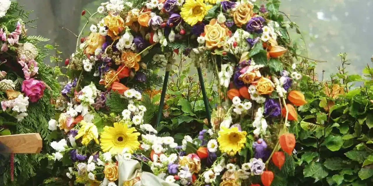 Bogaty wieniec pogrzebowy z róż, gerber, chryzantem i miechunki. Piękne kwiaty na wieniec pogrzebowy tworzą symboliczny bukiet.