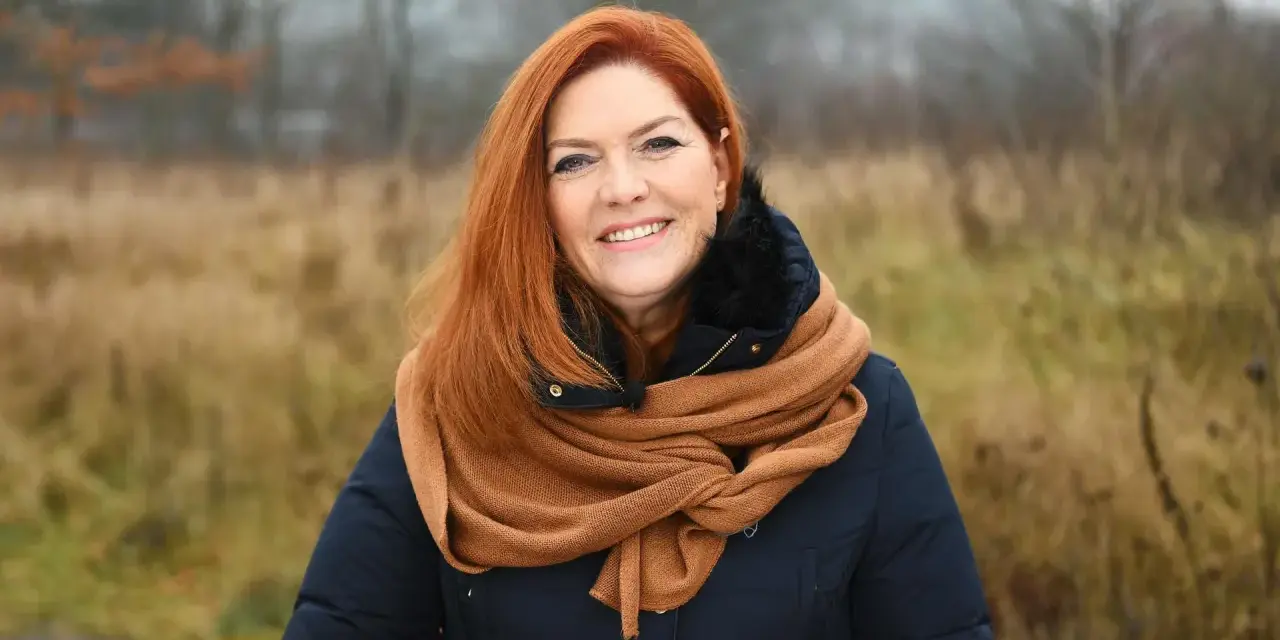 Uśmiechnięta Kasia w rudych włosach, otulona szalikiem, cieszy się listopadowym dniem.
