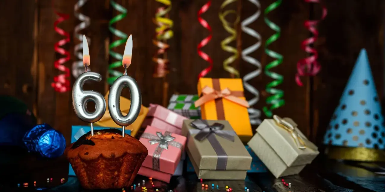 Urodzinowy muffin z cyframi 60, prezentami i serpentynami. Idealne życzenia na 60 urodziny!