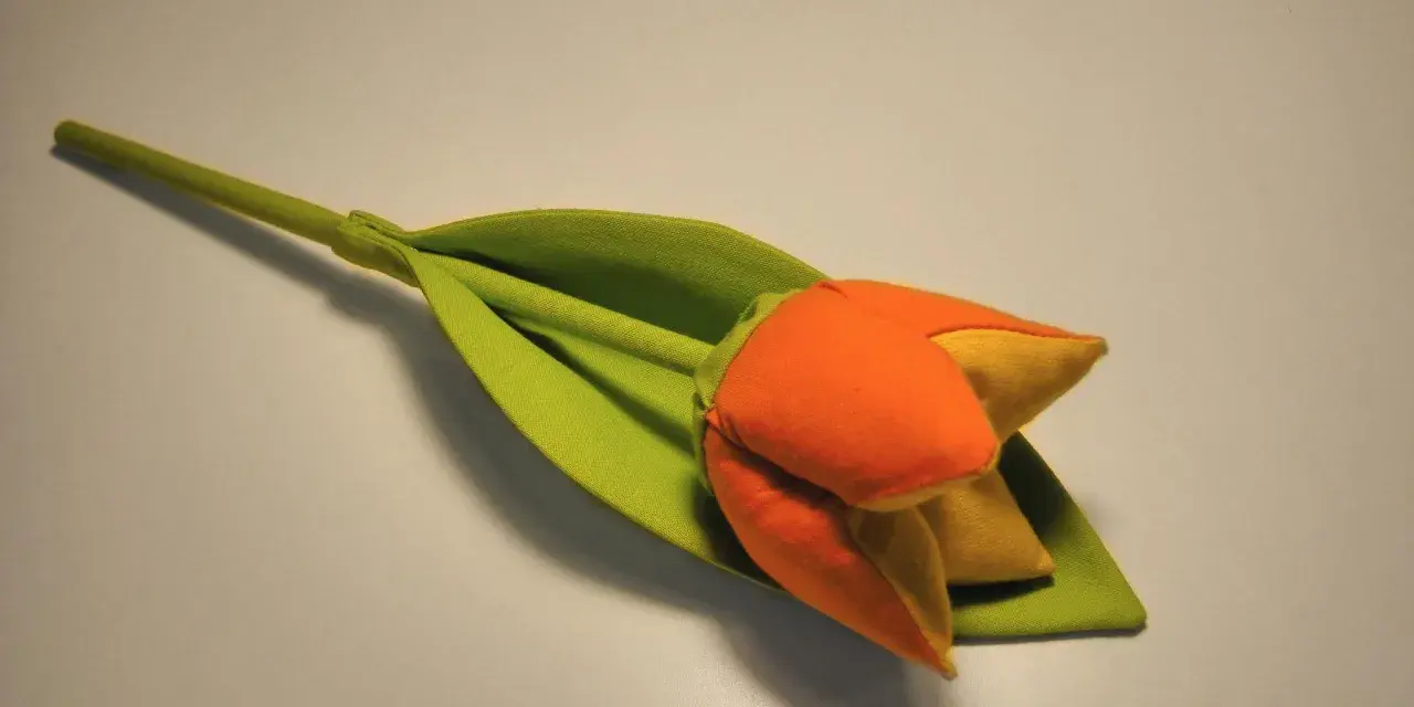 Pomarańczowo-żółty tulipan z zielonym liściem, jak suszyć tulipany, by zachować ich piękno.
