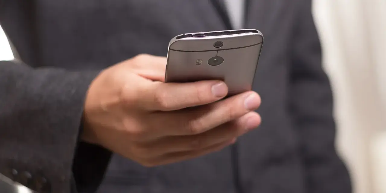 Mężczyzna w garniturze trzyma telefon, zastanawiając się, jak złożyć kondolencje przez telefon.