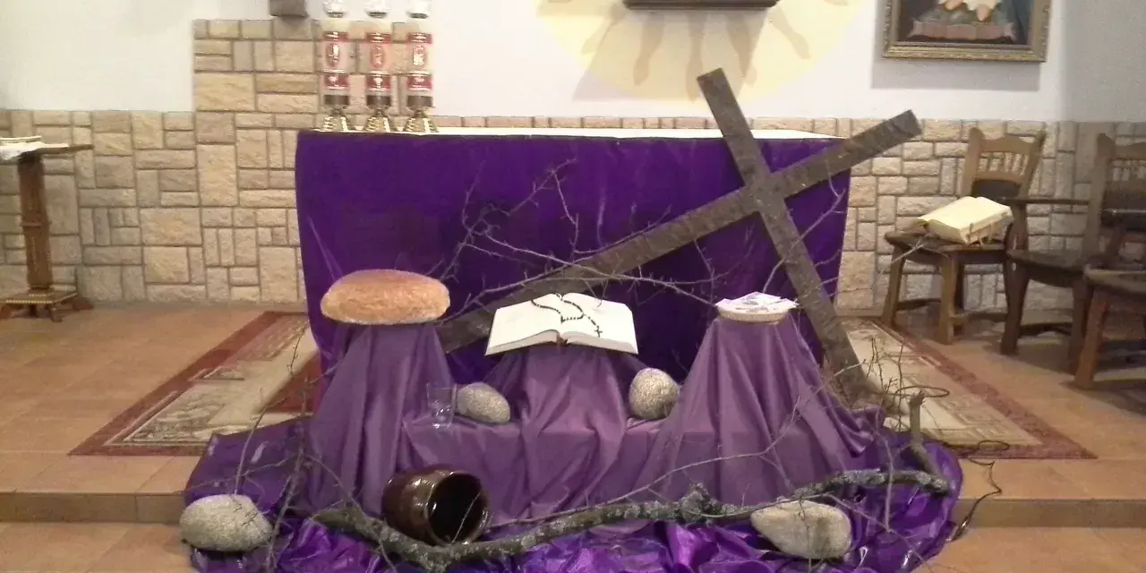 Wystrój kościoła na Wielkanoc: fioletowe tkaniny, krzyż, księga, bochenek chleba i kamienie symbolizują mękę i zmartwychwstanie.