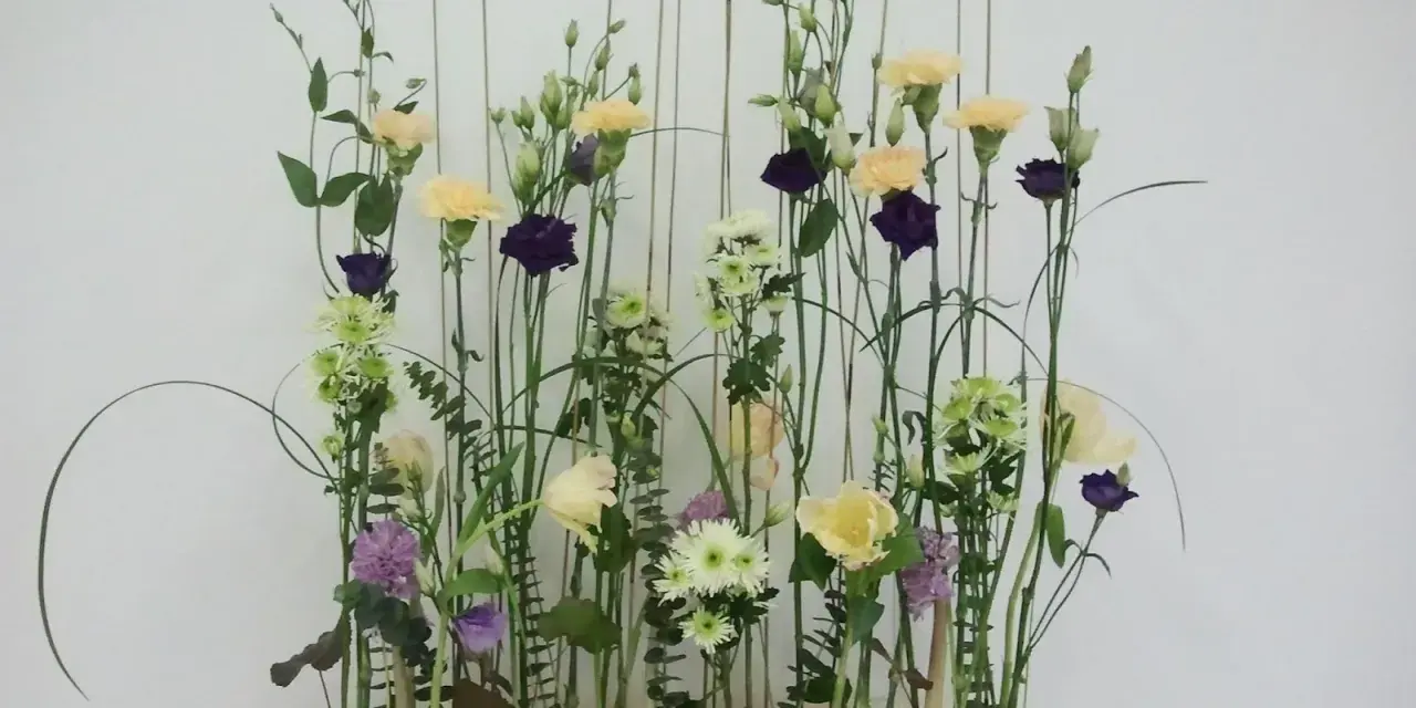 Kwiaty w pastelowych barwach i ciemnofioletowe akcenty, ułożone w stylu wegetatywnym we florystyce, tworzą lekki, naturalny bukiet.