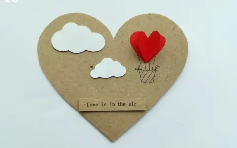 Serce z balonów w kształcie serca, unoszące się wśród chmur. Napis "Love is in the air".