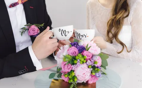 Para świętuje 4 rocznicę ślubu, trzymając kubki "Mr." i "Mrs." na tle bukietu kwiatów.