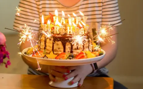 Urodzinowy tort z ogniem i owocami, idealny na mądre życzenia urodzinowe dla zięcia.