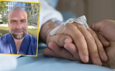 Uśmiechnięty mężczyzna w niebieskim uniformie medycznym dodaje słowa otuchy dla chorego, trzymając go za rękę.