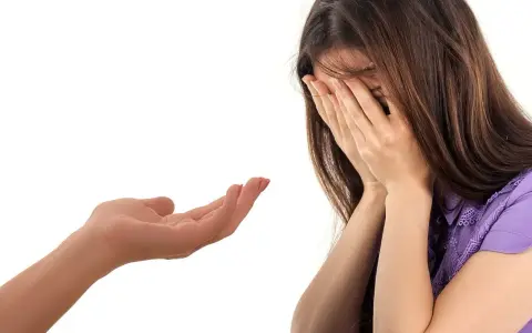 Wyciągnięta dłoń oferuje wsparcie. Kobieta ukrywa twarz w dłoniach, być może szukając przebaczenia. To obraz przeprosin dla przyjaciela.