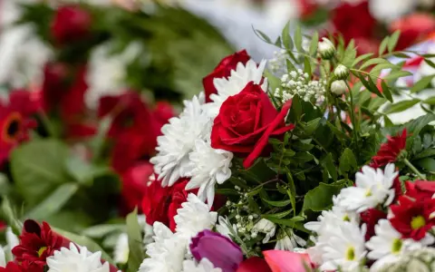 Napis na szarfie pogrzebowej dla brata: "Kochany Braciszku, na zawsze w sercu". Bukiet czerwonych róż i białych chryzantem.