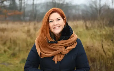 Uśmiechnięta Kasia w rudych włosach, otulona szalikiem, cieszy się listopadowym dniem.