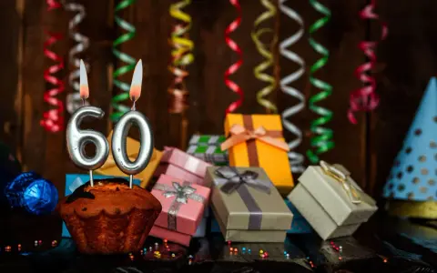 Urodzinowy muffin z cyframi 60, prezentami i serpentynami. Idealne życzenia na 60 urodziny!