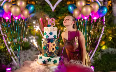 Dziewczyna zdmuchuje świeczki na torcie z okazji 18. urodzin. Balony i fajerwerki podkreślają uroczystość.
