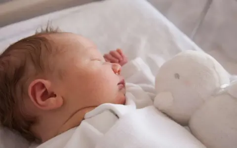 Słodki chłopczyk śpi obok białej przytulanki. Gratulacje z okazji narodzin syna!