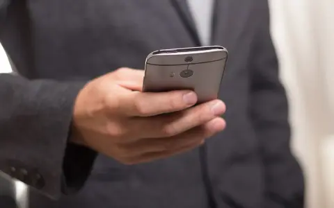 Mężczyzna w garniturze trzyma telefon, zastanawiając się, jak złożyć kondolencje przez telefon.