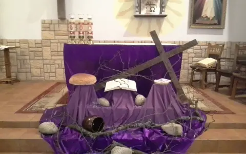 Wystrój kościoła na Wielkanoc: fioletowe tkaniny, krzyż, księga, bochenek chleba i kamienie symbolizują mękę i zmartwychwstanie.