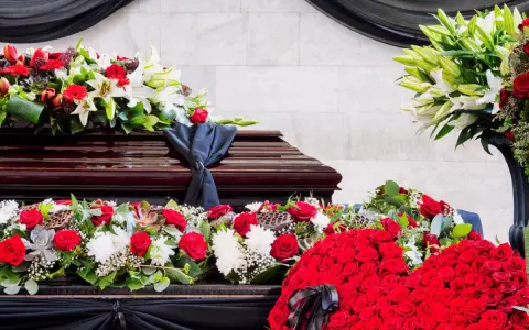 Bogata dekoracja kwiatowa, w tym róże i lilie, otacza trumnę. To piękny, pojedynczy kwiat na pogrzeb, symbolizujący pamięć i szacunek.