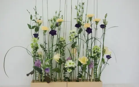 Kwiaty w pastelowych barwach i ciemnofioletowe akcenty, ułożone w stylu wegetatywnym we florystyce, tworzą lekki, naturalny bukiet.