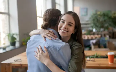 Uśmiechnięta dziewczyna mocno przytula przyjaciela. To szczere podziękowanie za pomoc i wsparcie.