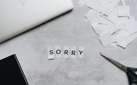 Litery wycięte z papieru układają się w napis "SORRY". Obok leżą nożyczki i stos białych skrawków, jakby ktoś tworzył piękny list na przeprosiny.