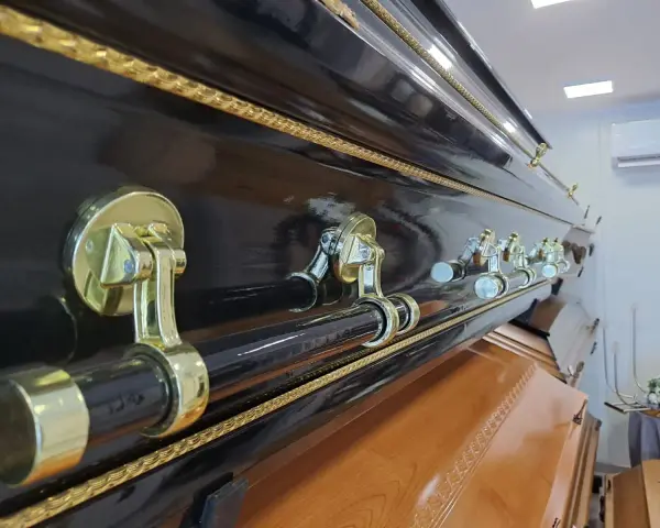Elegancka, czarna trumna z ozdobnymi uchwytami. Warto pomyśleć, jak napisać pożegnanie od zmarłego, by oddać mu hołd.