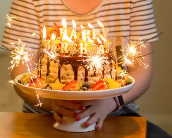 Urodzinowy tort z ogniem i owocami, idealny na mądre życzenia urodzinowe dla zięcia.