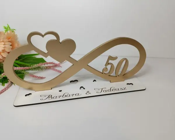 Złoty symbol nieskończoności z sercami i cyfrą 50. Na podstawie wygrawerowane imiona Barbara & Tadeusz. Idealna dekoracja na 50 rocznicę ślubu.