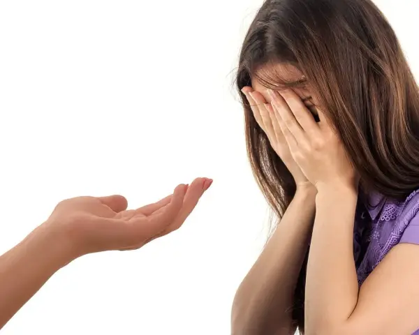 Wyciągnięta dłoń oferuje wsparcie. Kobieta ukrywa twarz w dłoniach, być może szukając przebaczenia. To obraz przeprosin dla przyjaciela.