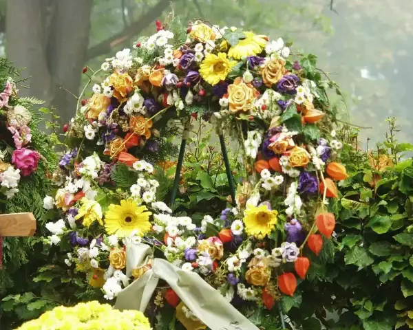 Bogaty wieniec pogrzebowy z róż, gerber, chryzantem i miechunki. Piękne kwiaty na wieniec pogrzebowy tworzą symboliczny bukiet.