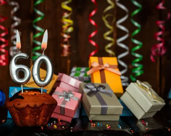 Urodzinowy muffin z cyframi 60, prezentami i serpentynami. Idealne życzenia na 60 urodziny!