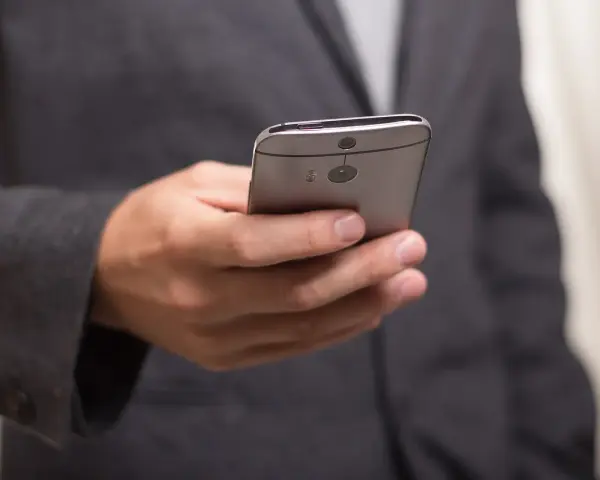Mężczyzna w garniturze trzyma telefon, zastanawiając się, jak złożyć kondolencje przez telefon.