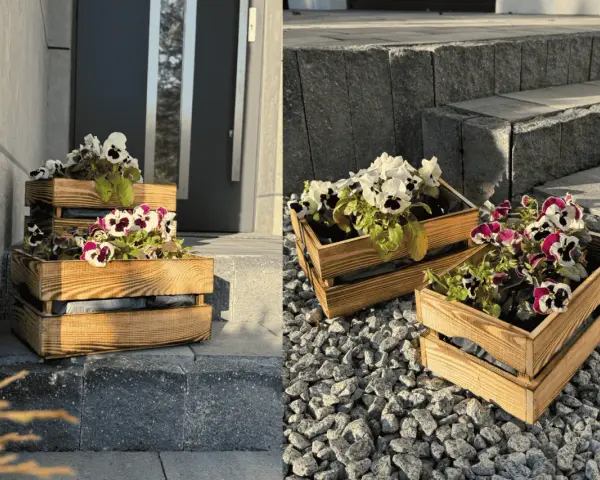 Drewniane skrzynki z kompozycjami kwiatowymi na balkon, ozdabiające wejście do domu.