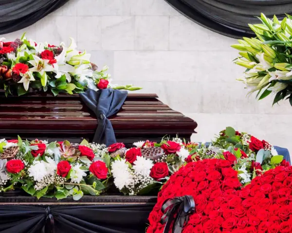 Bogata dekoracja kwiatowa, w tym róże i lilie, otacza trumnę. To piękny, pojedynczy kwiat na pogrzeb, symbolizujący pamięć i szacunek.