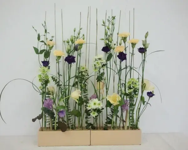 Kwiaty w pastelowych barwach i ciemnofioletowe akcenty, ułożone w stylu wegetatywnym we florystyce, tworzą lekki, naturalny bukiet.