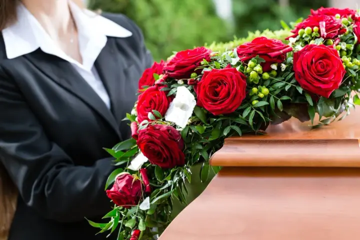 Czerwone róże, tradycyjne kwiaty na pogrzeb, zdobią drewnianą trumnę.