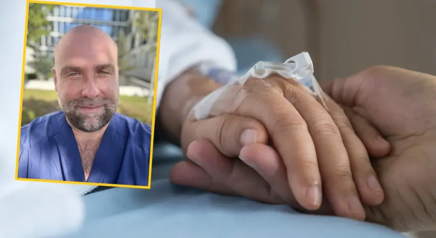 Uśmiechnięty mężczyzna w niebieskim uniformie medycznym dodaje słowa otuchy dla chorego, trzymając go za rękę.