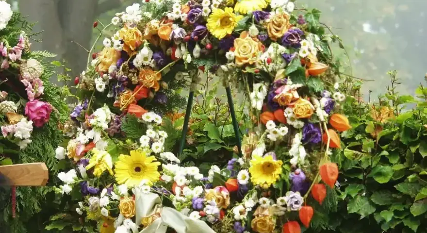 Bogaty wieniec pogrzebowy z róż, gerber, chryzantem i miechunki. Piękne kwiaty na wieniec pogrzebowy tworzą symboliczny bukiet.