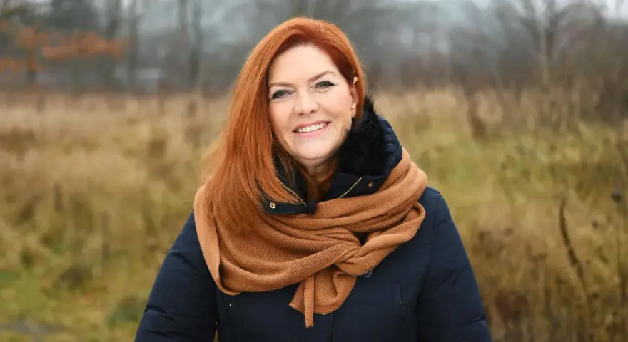 Uśmiechnięta Kasia w rudych włosach, otulona szalikiem, cieszy się listopadowym dniem.